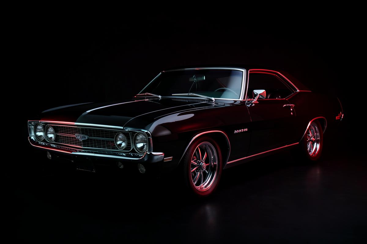 Restored classic muscle car lit in a dark studio